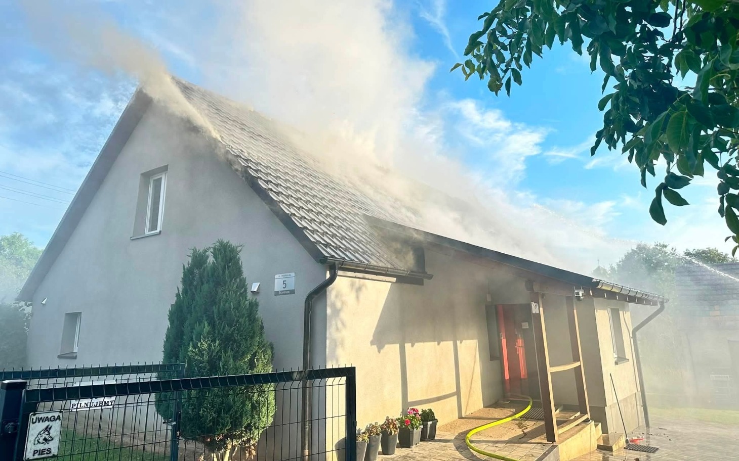 
        Szare budynki, teren pożarniczy z gaśnicą w dole kadru.
    