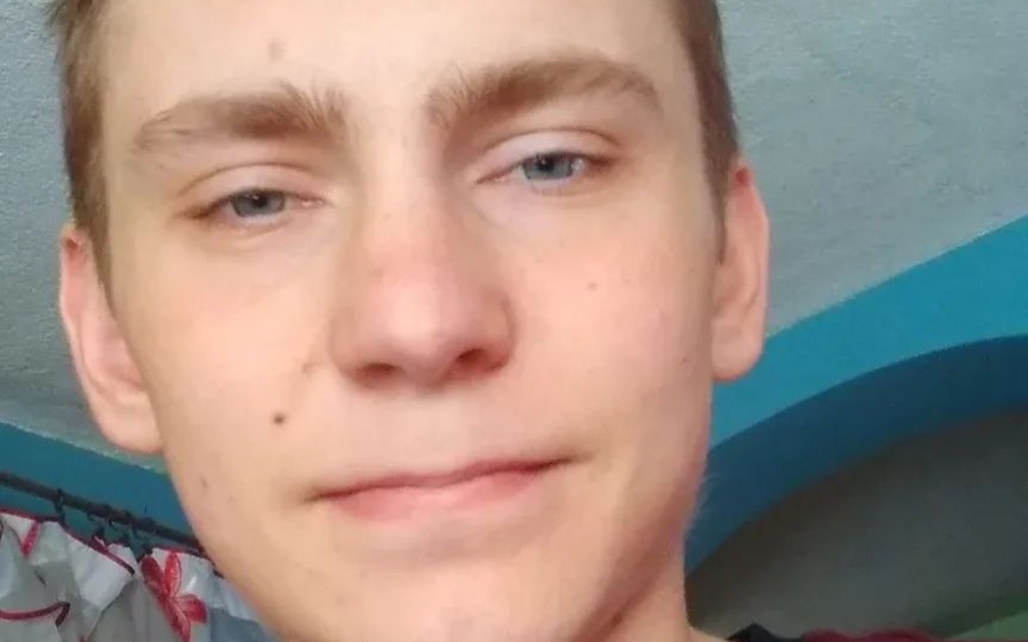 
        Zbliżenie na twarz młodego mężczyzny, częściowo uśmiech.
    