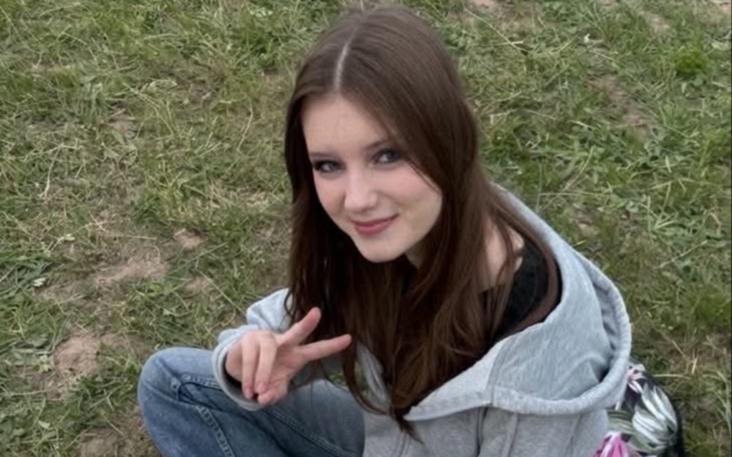 
        Uśmiechnięta nastolatka siedzi na trawie i pozuje do zdjęcia.
    