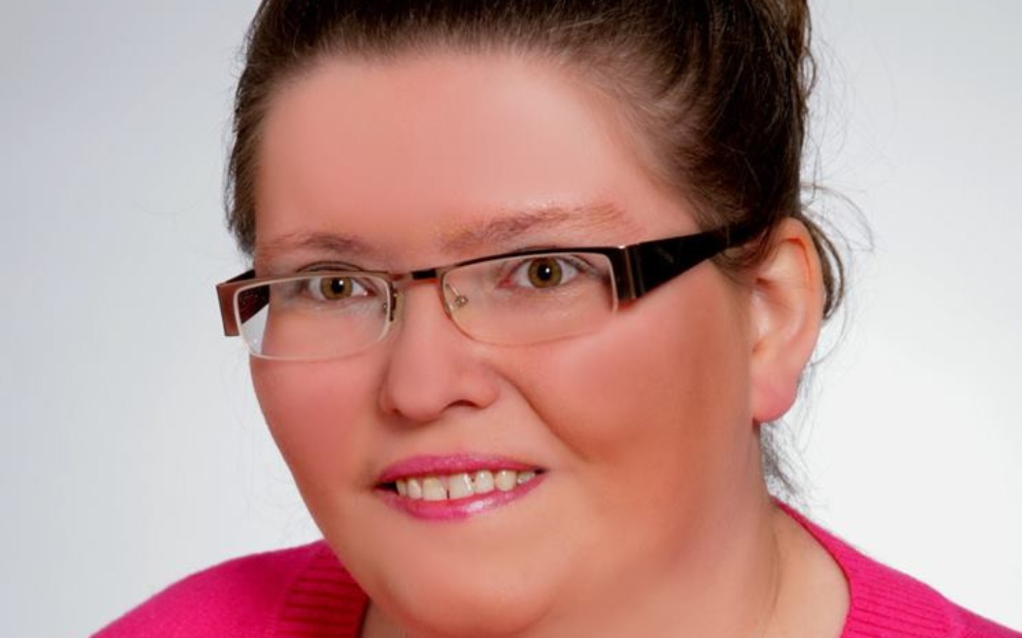 
        Kobieta w okularach, uśmiechająca się do kamery.
    