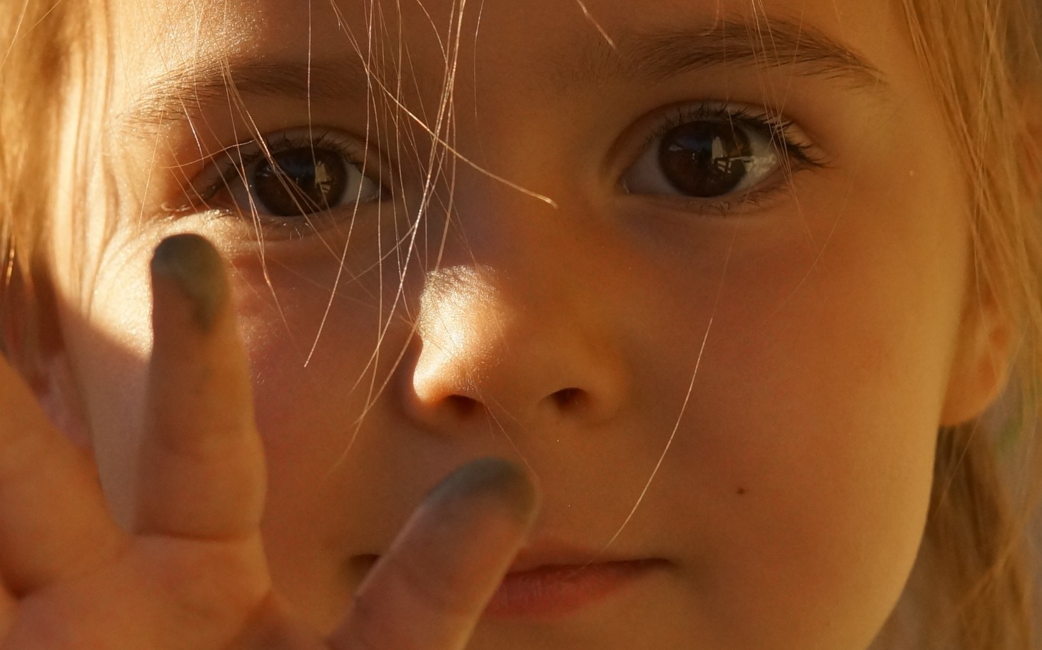 
        Mała dziewczynka z brudnymi palcami, uśmiechająca się.
    